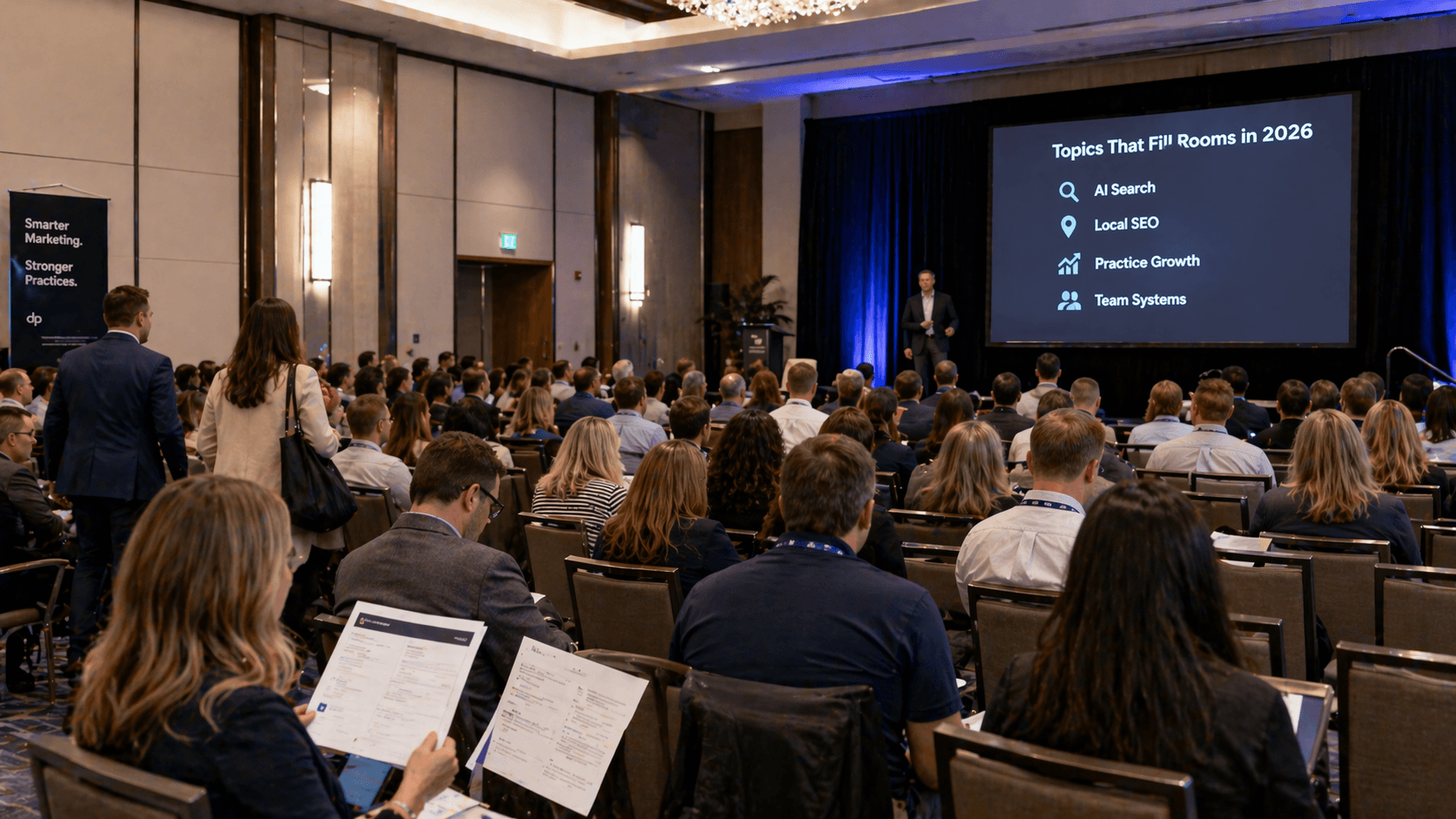 Packed dental conference session with a speaker presenting 2026 topics that fill rooms, including AI search, local SEO, practice growth, and team systems